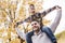 Happy family father and child boy on his shoulder in the autumn leaf fall in park