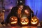 Happy family father and daughter in Halloween costumes looking inside of glowing jack-o-lantern