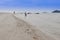 Happy family - father hold baby hand walk in sea on summer vacations with children