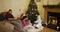 Happy family of five sits near Christmas tree and looks at gifts at home, girl gives a gift to his father. Shot in 4k