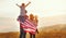 Happy family with flag of america USA at sunset outdoors