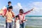 Happy family of four spend time together on tropical sand beach, father and mother playing with kid, daddy carrying cute little