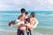 Happy family of four spend time together on tropical sand beach, father playing with kid, daddy carrying cute son, lifting his boy