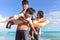 Happy family of four spend time together on tropical sand beach, father playing with kid, daddy carrying cute son, lifting his boy