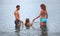 Happy family with girl bathe in sea, standing back
