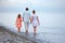 Happy family with girl walk on beach in evening