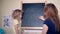 Happy family girls mom and daughter writing word father on black chalk board