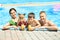 Happy family with glasses of juice resting in swimming pool