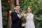 Happy family of groom and bride at wedding day ceremory with arch and retro lightbulb on background shows their hands