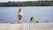 Happy family have vacations at the lake. Mother with son jump from the pier together. Boy diving from the dock into the