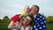 Happy family holding american flag in the park on a sunny day. Outdoor portrait. Independence Day, July 4