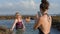 Happy family on holiday at ocean shore. Adult woman taking picture of senior woman as they are standing in sea water