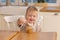 Happy family at home. Baby boy feeding himself in kitchen. Little boy with messy funny face eats healthy food. Child