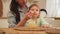 Happy family at home. Mother feeding her baby girl from spoon in kitchen. Little toddler child with messy funny face