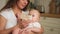 Happy family at home. Mother holding little baby toddler child feeding milk from bottle. Newborn Infant baby girl