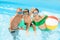 Happy family with inflatable ring and ball resting in swimming pool