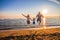 Happy family jump on the shore on sunset light