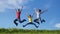 Happy family jumping on green grass hill against blue sky