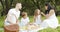 Happy family with kids resting on the grass during a picnic in the picturesque green garden. Outdoors.