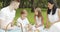 Happy family with kids resting on the grass during a picnic in the picturesque green garden. Outdoors