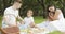 Happy family with kids resting on the grass during a picnic in the picturesque green garden. Outdoors.