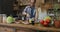 Happy family in kitchen cooking food while son filming video of parents and sister preparing meal together