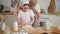 Happy family in kitchen. Grandmother and granddaughter child cook in kitchen together. Grandma teaching kid girl knead