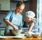 Happy family in kitchen. mother and child preparing dough, bake