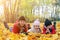 happy family lies on yellow maple leaves in sunny park. mother with kids enjoying fall weather outdoors