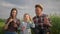 Happy family, little boy with mom and dad blowing soap bubbles during fun leisure on nature in field against sky