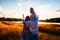 Happy family with a little daughter in a field in nature, looking forward, view from the back, in the rays of the sunset