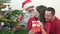 Happy family looking surprised at gift box close Christmas tree, playful child