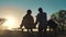 Happy family man and girl teamwork sitting on a bench silhouette sunset in the park and nature. dad and daughter relax