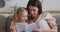 Happy family mom and kid daughter reading book at home