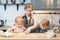 Happy family mom and two cute daughters preparing homemade cookies in the kitchen