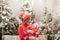 Happy family mother and child boy in santa hat near snow covered Christmas trees with sitting on swing. Bright garland