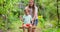 Happy family, mother and child play on wooden swing in garden under tree