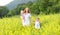 happy family, mother and children little daughter and baby running on meadow with yellow flowers