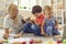 Happy family mother and children sitting on floor and playing together at home