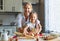 Happy family mother and daughter bake kneading dough in kitchen