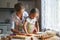 Happy family mother and daughter bake kneading dough in kitchen
