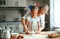 Happy family mother and daughter bake kneading dough in kitchen