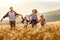 Happy family: mother, father, children son and daughter runing and jumping on sunset