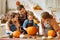 Happy family mother, father and kids to remove pulp from from pumpkin while carving jack o lantern with family