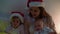 happy family mother in red santa hat two children babies little baby siblings Christmas night in bed pajamas have fun