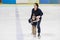 Happy family, mother teaches son ice skating at rink.