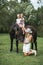 Happy family, mother with two children cute daughters riding a horse. Mother in white dress, hat and cowboy boots