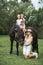 Happy family, mother with two children cute daughters riding a horse. Mother in white dress, hat and cowboy boots