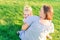 Happy family on nature. Mom and toddler baby daughter relaxing, hugging, laughing and have fun on green grass meadow at evening su