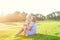 Happy family on nature. Mom and toddler baby daughter relaxing, hugging, laughing and have fun on green grass meadow at evening su